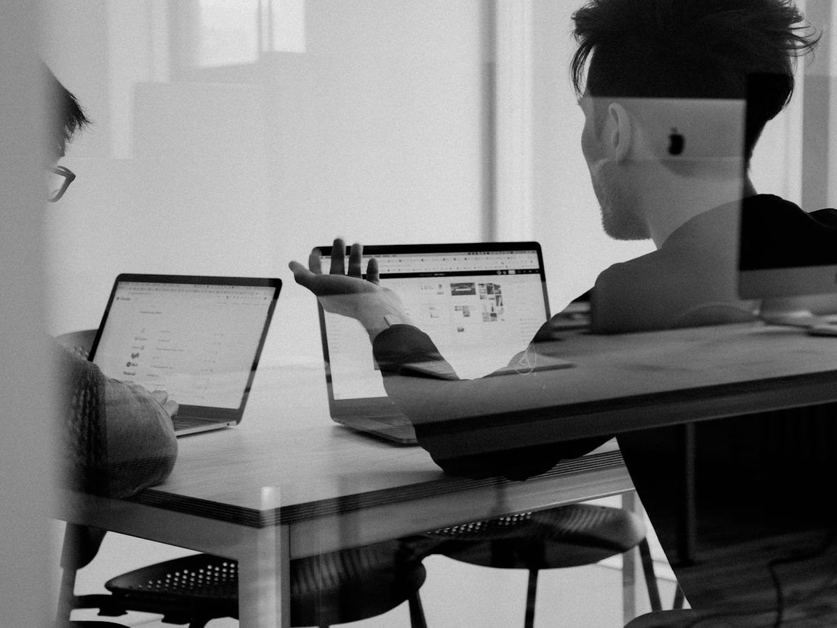 Two people working side by side at laptops in a quiet office